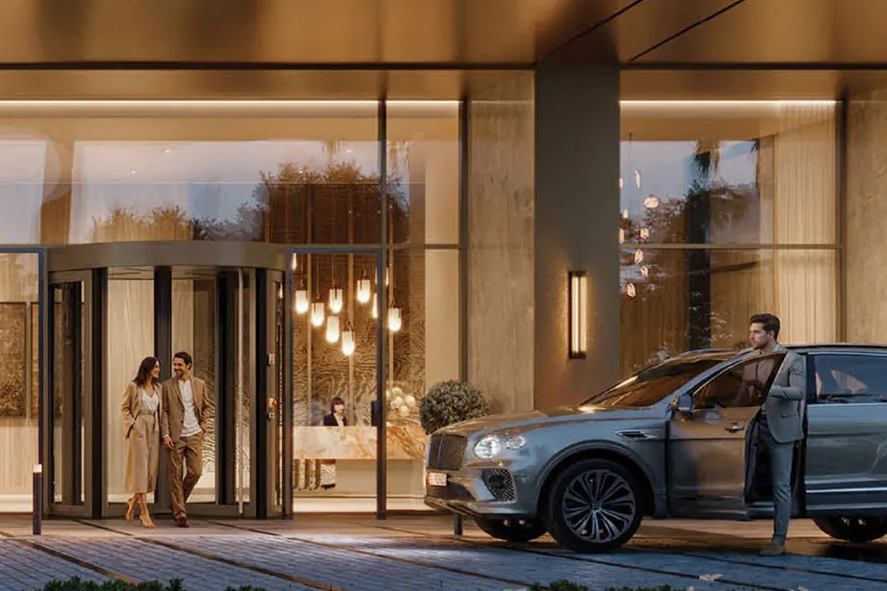 Couple leaving the glowing entrance as a car waits at the drop-off